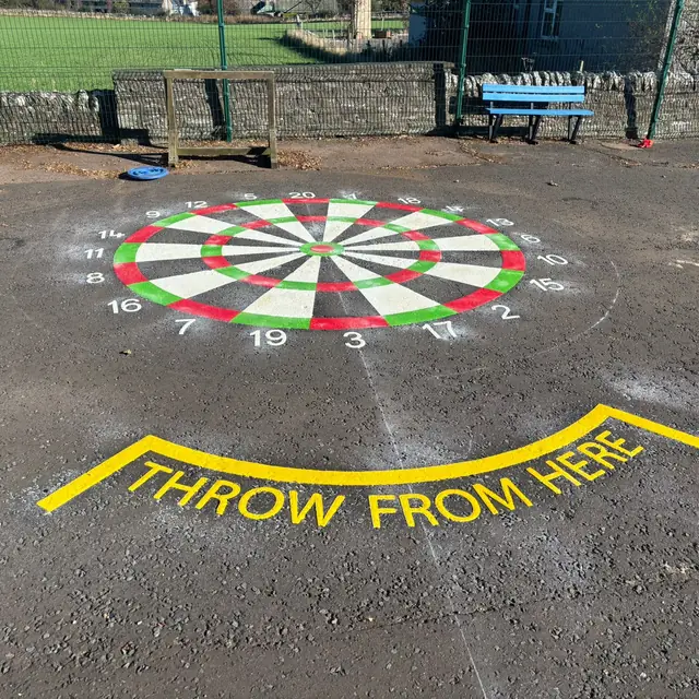 A large dartboard marking with a yellow line reading throw from here