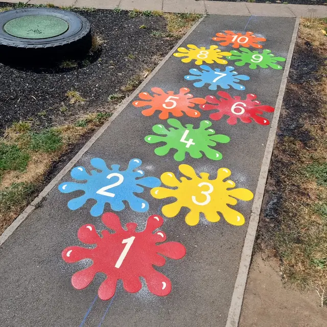 Bright paint splats numbered 1 to 10 along a playground path