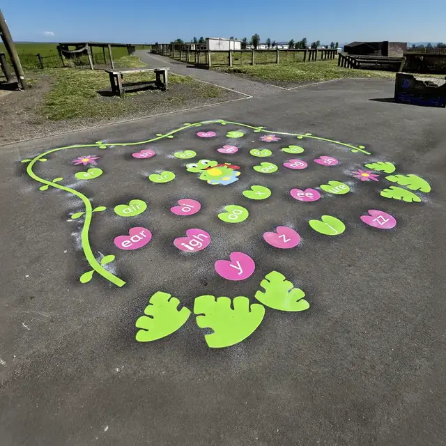 Pink and green lily pads with letter sounds, a frog and a winding vine on a playground